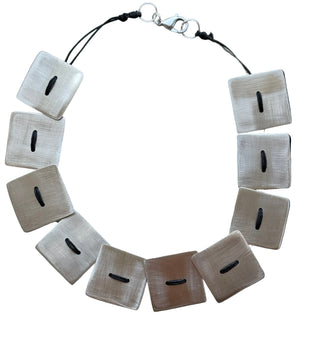 Necklace with square metallic pendants on a light background